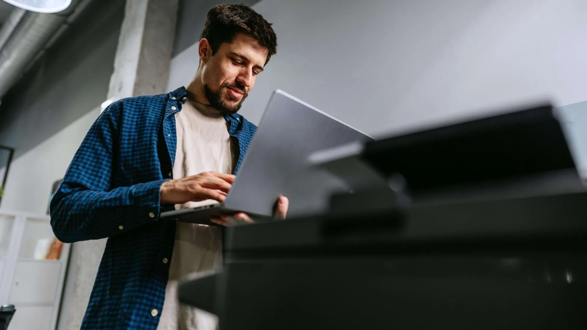 Auszubildender Fachinformatiker für Systemintegration arbeitet mit Laptop und Drucker., Bild öffnen