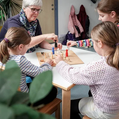 Erzieherin spielt mit Kindern Mensch ärgere dich nicht
