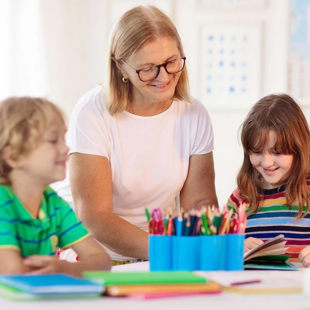 Kinderpflegerin betreut mehrere Kinder beim gemeinsamen Spielen. Kinderpflegerin betreut mehrere Kinder beim gemeinsamen Spielen.