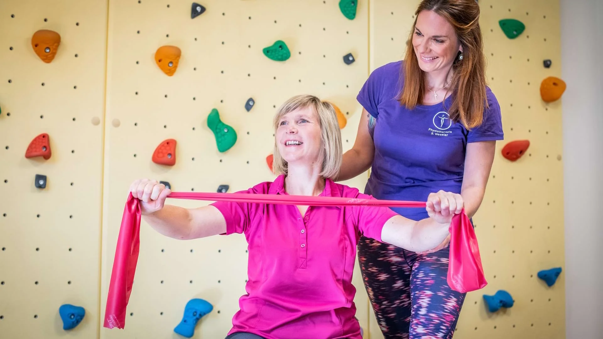 Physiotherapeutin Sarah Wessler begleitet eine Patientin bei einer aktiven Therapieübung mit Trainingsbändern.