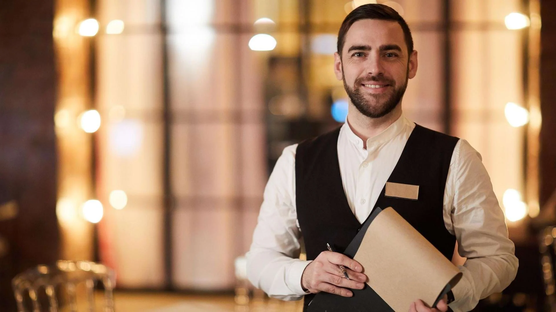 Auszubildende Hotelfachkraft steht im Servicebereich und hält Unterlagen in der Hand. Auszubildende Hotelfachkraft steht im Servicebereich und hält Unterlagen in der Hand., Bild öffnen