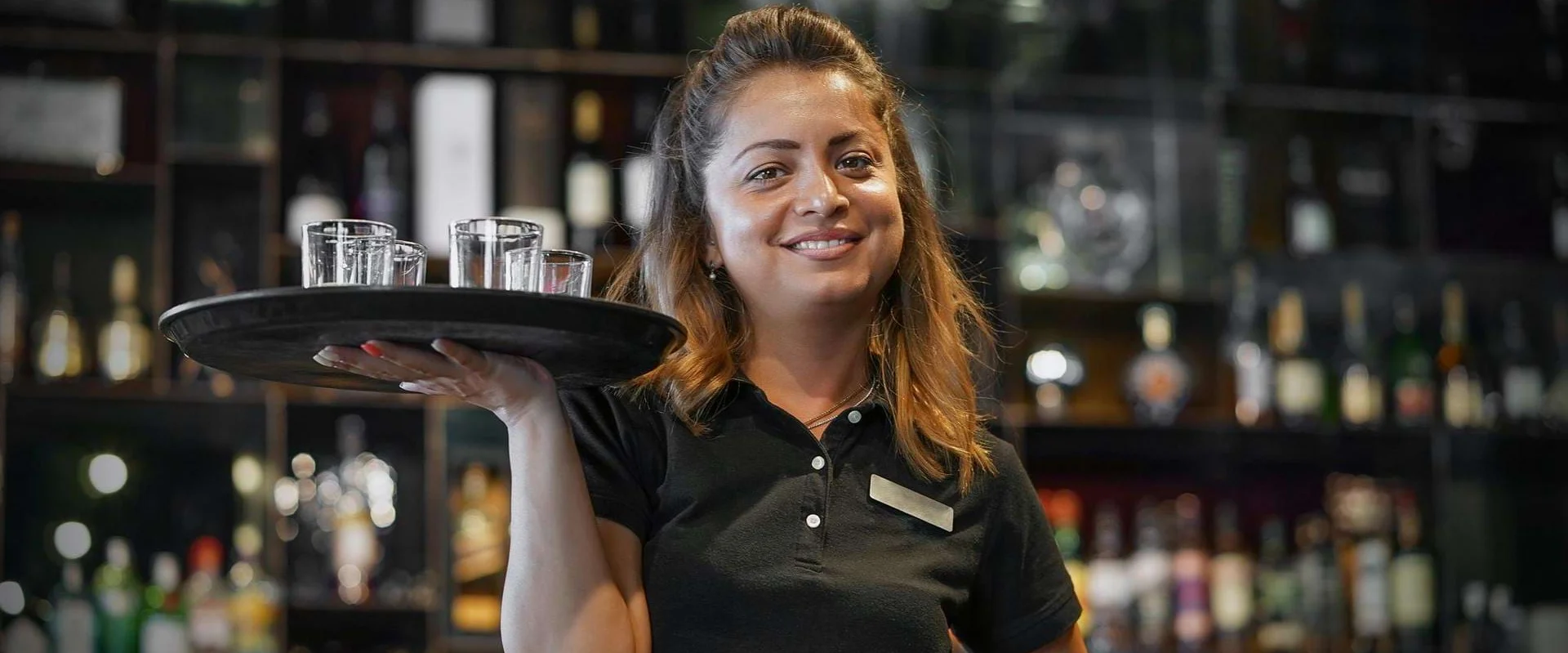 Eine Auszubildende zur Fachkraft für Gastronomie arbeitet mit Tablet im Service.