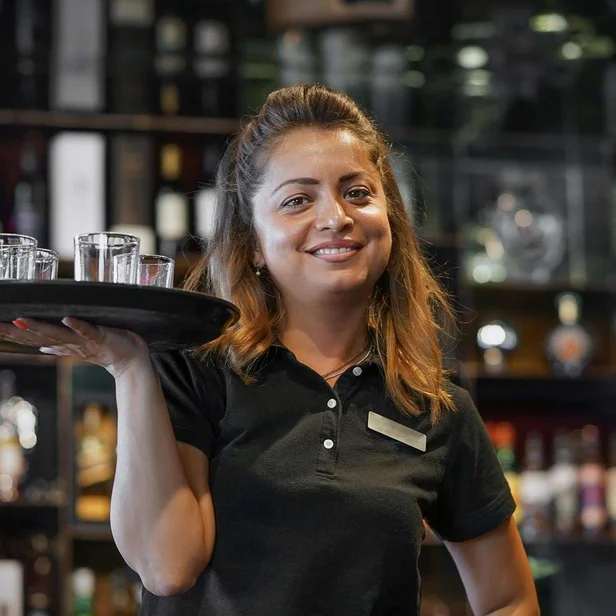 Eine Auszubildende zur Fachkraft für Gastronomie arbeitet mit Tablet im Service. Eine Auszubildende zur Fachkraft für Gastronomie arbeitet mit Tablet im Service.